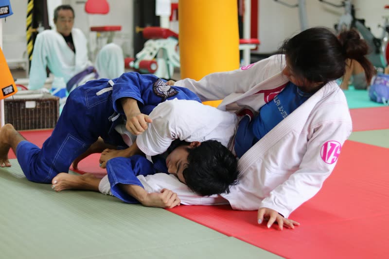 Duas crianças de quimono treinando jiu-jítsu no tatame